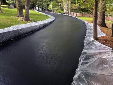 Sealcoating crew spraying asphalt sealer in Hudson County NJ