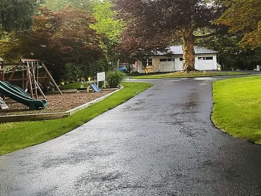 Sealcoating technician spraying asphalt protection in Bergen County NJ