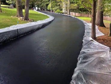 Sealcoating technician spraying asphalt protection in Bergen County NJ